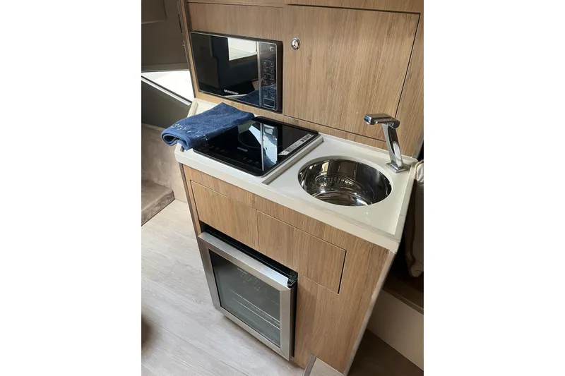 Slide: The Image of Compact kitchenette in 2023 NX Boats NX360 with sink, stove, and microwave. - 25