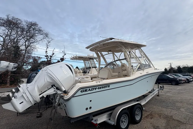 Slide: The Image of 2024 Grady-White Freedom 255 boat on trailer, parked outdoors under cloudy sky. - 3