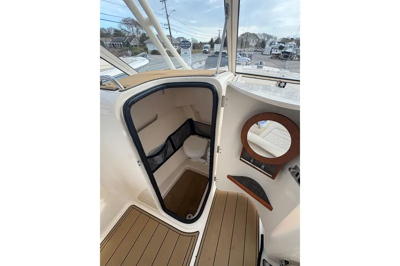Slide: The Image of 2024 Grady-White Freedom 255 boat interior with open cabin door and visible toilet. - 7