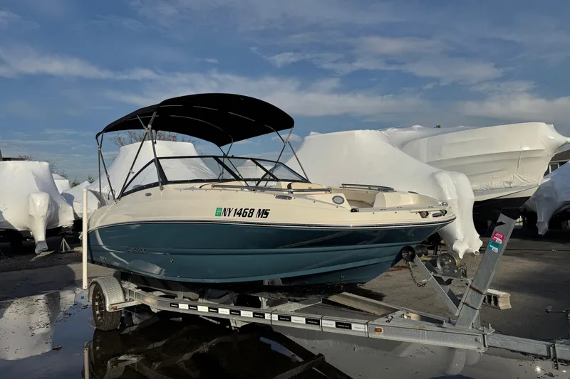 The Image of 2021 Stingray 201 DC boat on trailer, parked outdoors under blue sky. - 1
