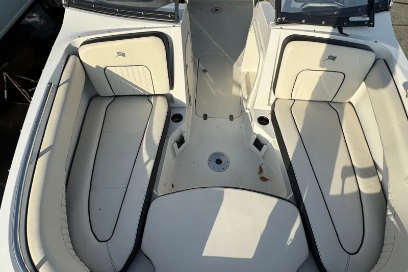 Slide: The Image of 2021 Stingray 201 DC boat interior with white cushioned seating and cup holders. - 14