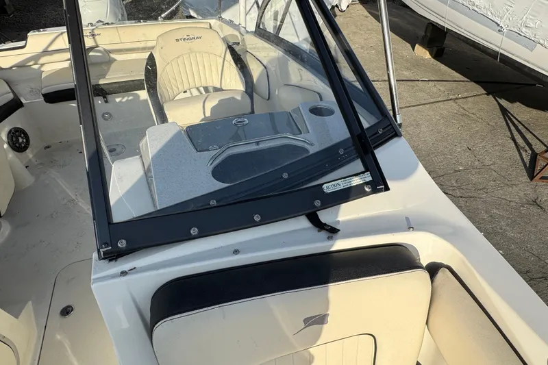 Slide: The Image of 2021 Stingray 201 DC boat interior with beige seating and windshield. - 20