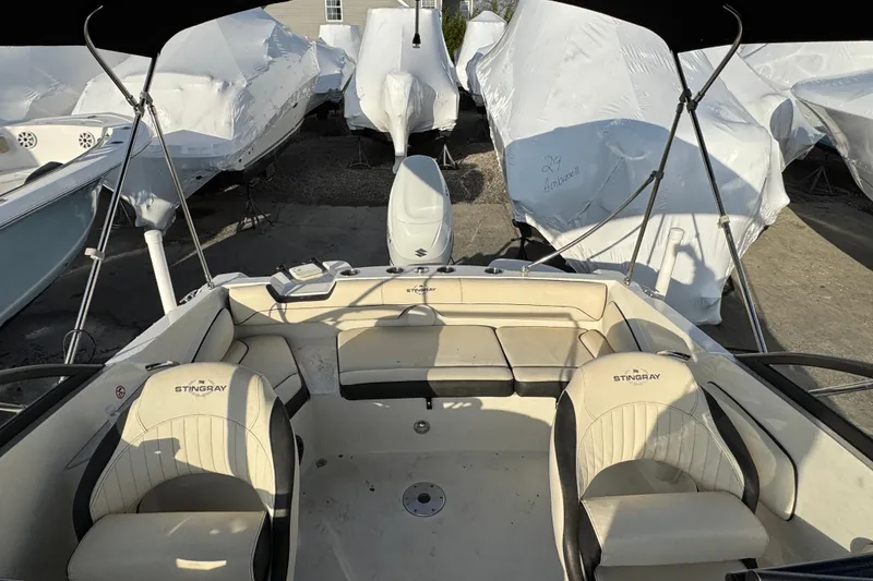 Slide: The Image of 2021 Stingray 201 DC boat interior with seating, surrounded by covered boats. - 21