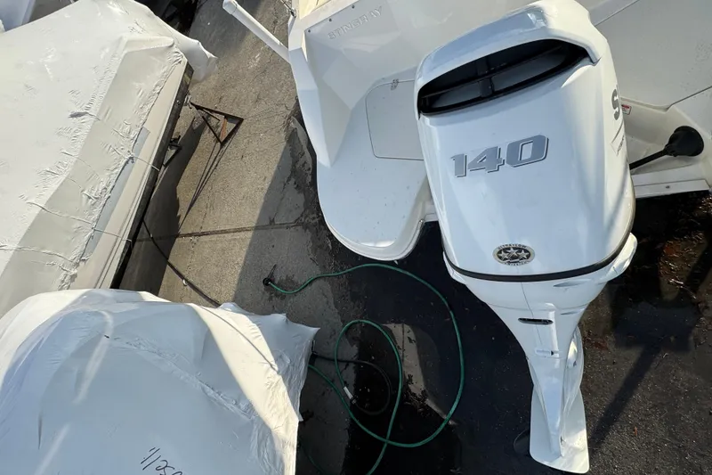 Slide: The Image of 2021 Stingray 201 DC boat with 140 HP outboard motor, covered in storage. - 22