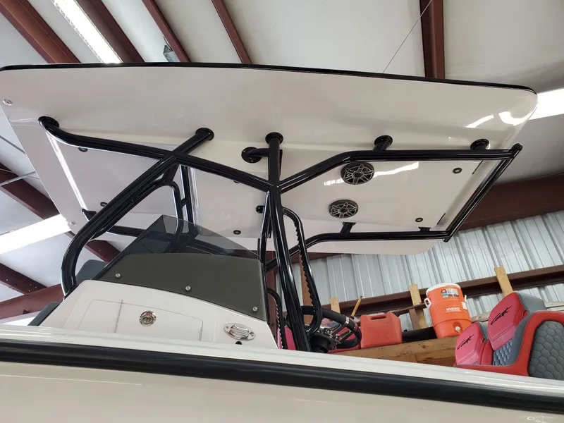 Slide: The Image of 2025 Concept Boats 27' CC center console with T-top and speakers in a warehouse. - 2