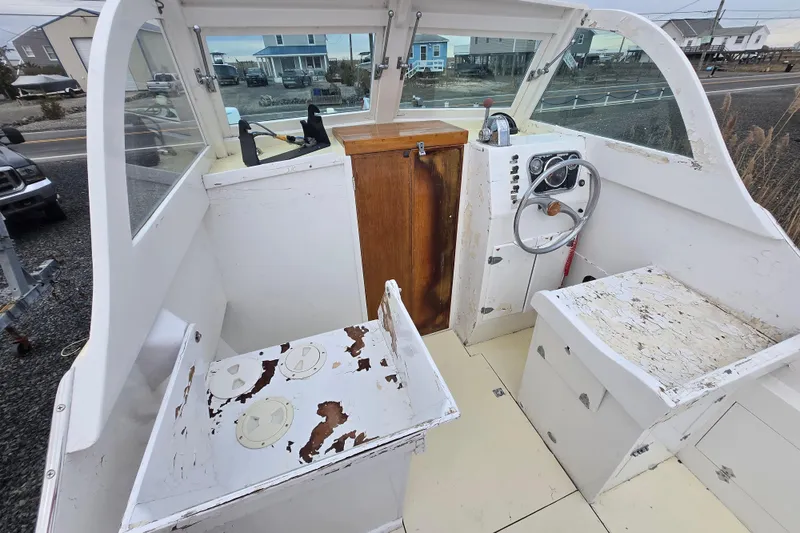 Slide: The Image of 1964 Whiticar 24 boat interior with weathered seats and steering wheel, docked near coastal homes. - 13