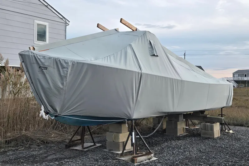 Slide: The Image of Covered 1964 Whiticar 24 boat on stands, near a house, under a cloudy sky. - 23