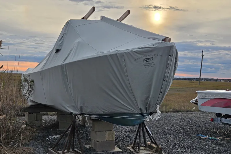 Slide: The Image of Covered 1964 Whiticar 24 boat on stands at sunset, with a scenic field backdrop. - 25