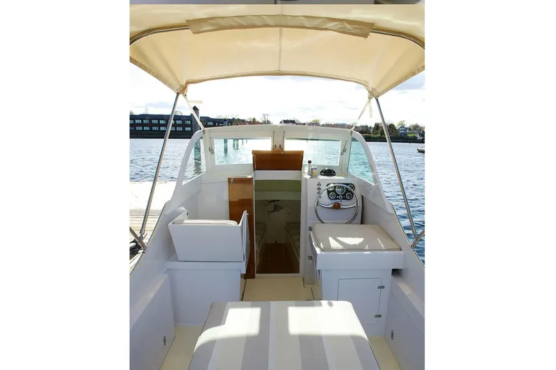 Slide: The Image of 1964 Whiticar 24 boat interior with helm, seating, and canopy on calm water. - 33