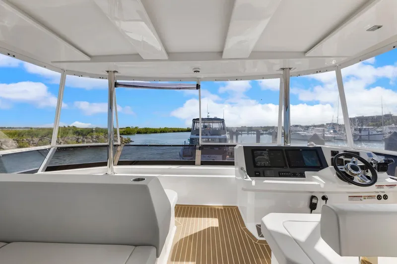 Slide: The Image of 2024 Leopard 46 Powercat helm with panoramic marina view, featuring modern controls and seating. - 18