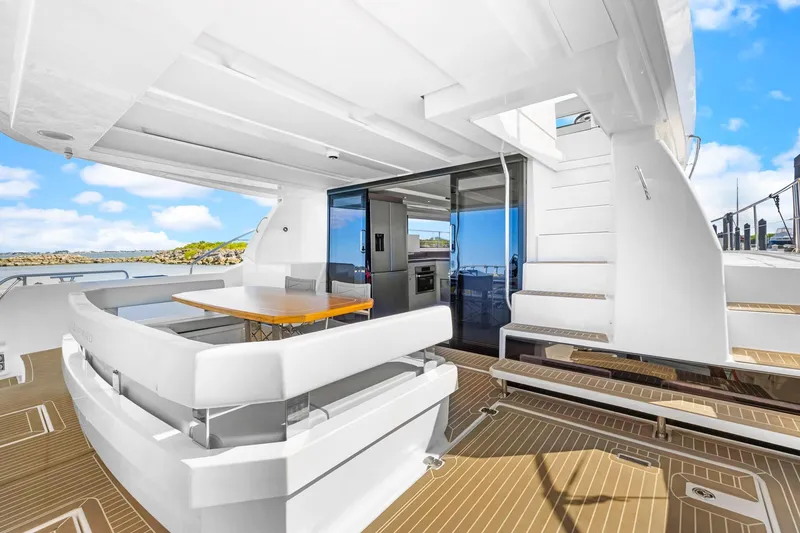 Slide: The Image of 2024 Leopard 46 Powercat yacht deck with seating, table, and stairs, under clear skies. - 40
