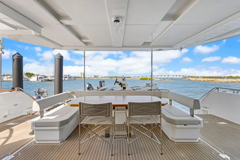 Slide: The Image of 2024 Leopard 46 Powercat yacht deck with seating, table, and scenic water view. - 5