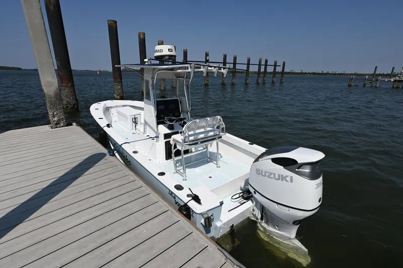 Slide: The Image of 1983 SeaVee 260B boat docked, featuring a Suzuki outboard motor, under clear blue skies. - 10