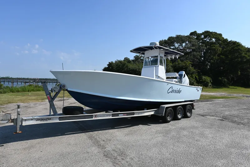 Slide: The Image of 1983 SeaVee 260B boat on trailer, parked outdoors under clear blue sky. - 15