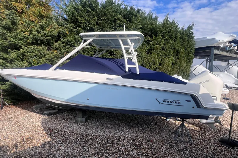 Slide: The Image of 2020 Boston Whaler 230 Vantage boat on gravel, surrounded by trees. - 3