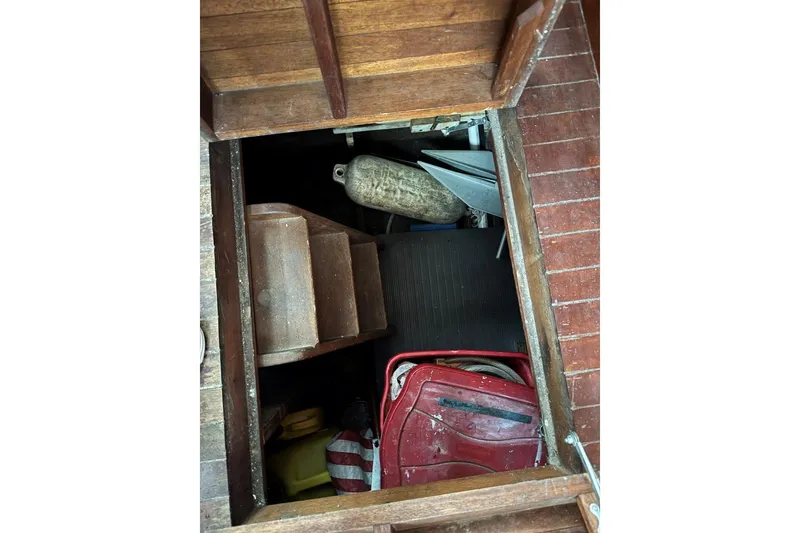 Slide: The Image of Wooden boat storage compartment with various items, including a fender and red container, Custom Cedar Craft 1987. - 16