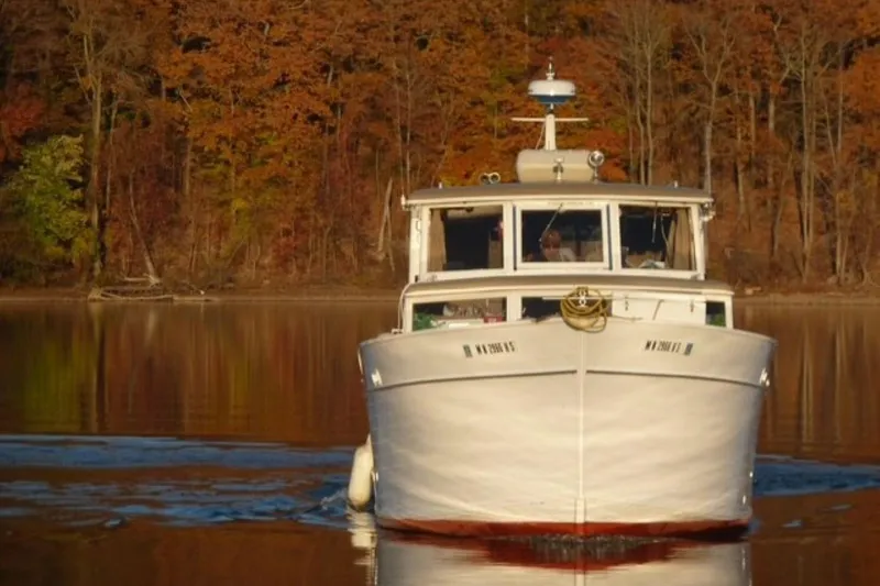 Slide: The Image of Front view of a 1987 Custom Cedar Craft boat on a calm lake with autumn trees. - 2