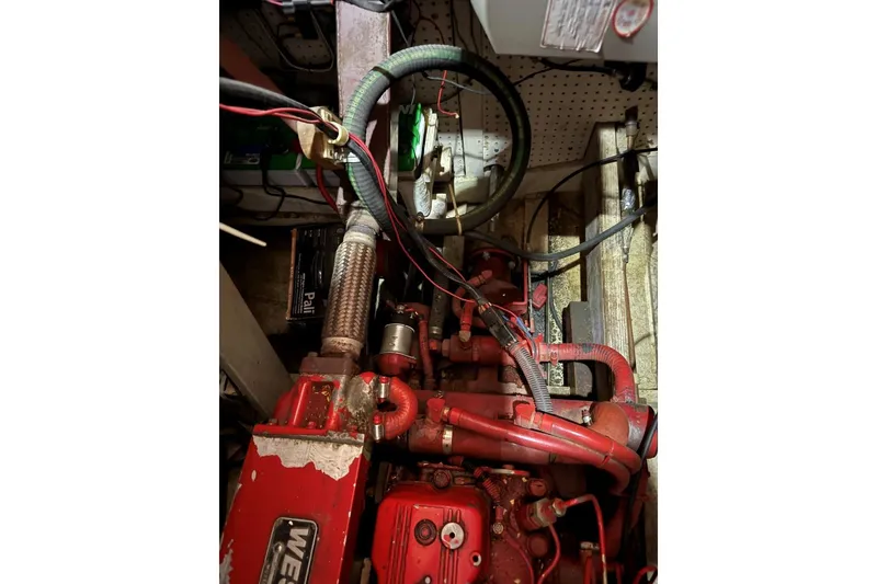 Slide: The Image of Red engine components in a 1987 Custom Cedar Craft boat, featuring hoses and wiring. - 37