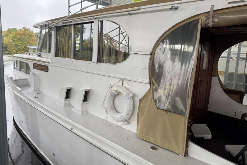 Slide: The Image of Custom 1987 Cedar Craft boat with white exterior and life preserver, docked near trees. - 6