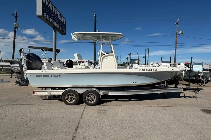 Slide: The Image of 2023 Skeeter SX2550 Family boat on trailer at dealership under clear blue sky. - 1
