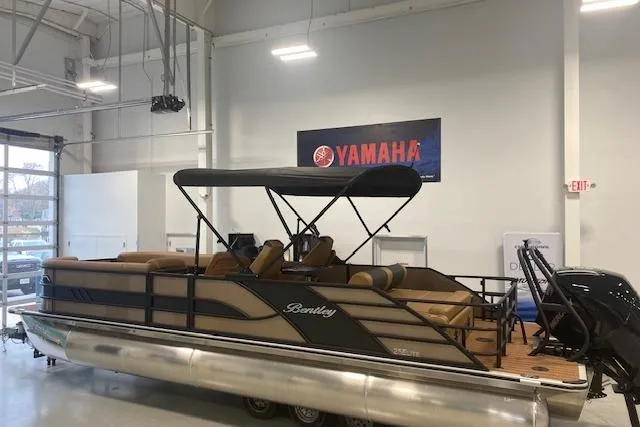 Slide: The Image of 2026 Bentley Pontoons Elite 253 Swingback in showroom with Yamaha signage. - 1