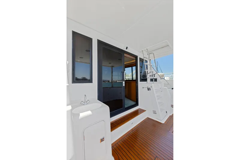 Slide: The Image of 1999 Symbol 558 yacht deck with wooden flooring, sink, and stairs leading to upper level. - 10