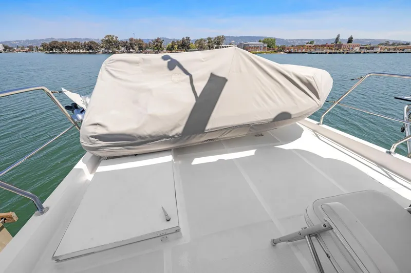 Slide: The Image of 1999 Symbol 558 yacht deck with covered equipment, overlooking calm waters and distant shoreline. - 26