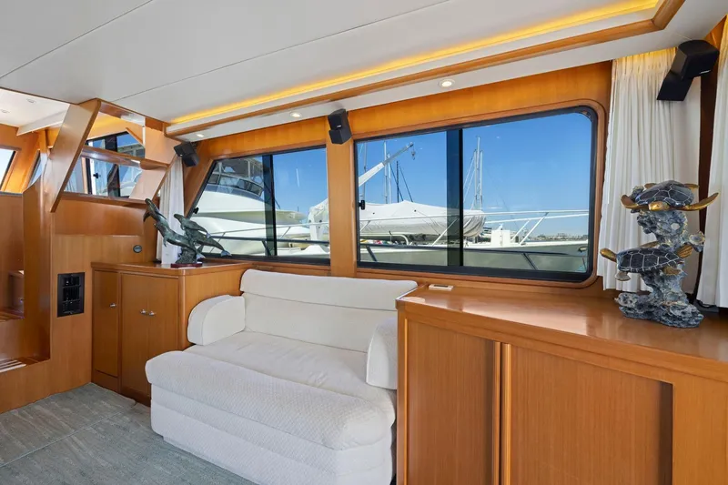 Slide: The Image of Luxurious yacht interior with wooden cabinetry, white sofa, and large windows showcasing marina views. - 31