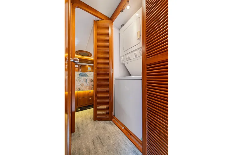 Slide: The Image of Laundry area with stacked washer-dryer in 1999 Symbol 558 yacht, featuring wooden louvered doors. - 47