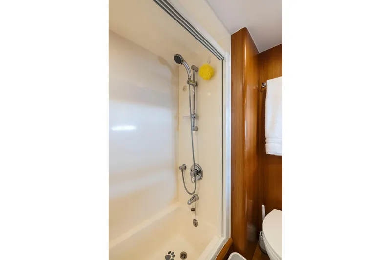 Slide: The Image of Shower area in a 1999 Symbol 558 yacht, featuring a handheld showerhead and wooden accents. - 54