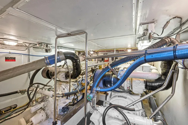 Slide: The Image of Engine room of a 1999 Symbol 558 yacht, featuring complex machinery and piping. - 59