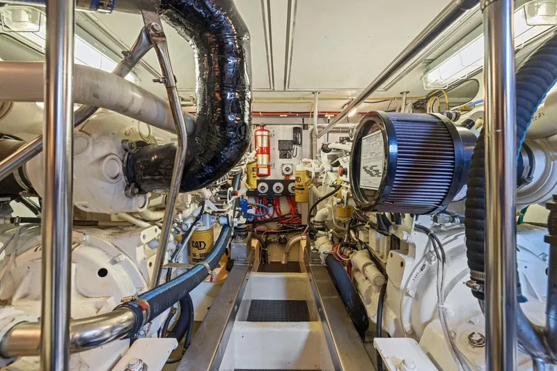 Slide: The Image of Engine room of a 1999 Symbol 558 yacht, featuring complex machinery and piping. - 61