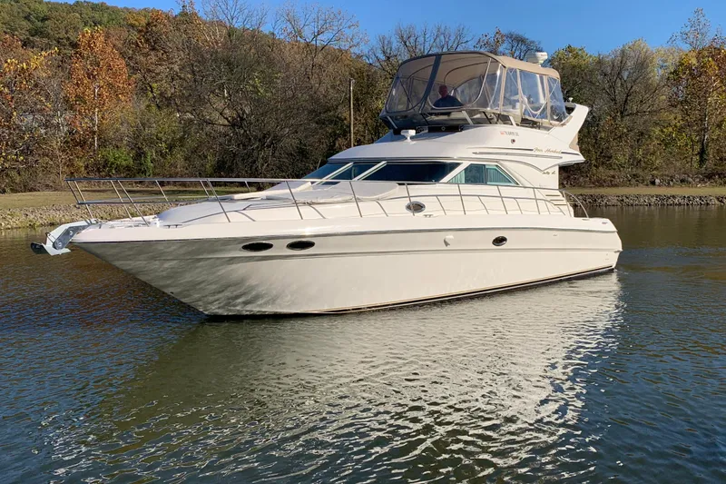 The Image of 2000 Sea Ray 400 Sedan Bridge yacht on calm water, surrounded by autumn trees. - 0
