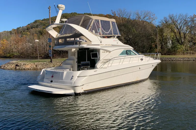 Slide: The Image of 2000 Sea Ray 400 Sedan Bridge yacht on a calm river, surrounded by autumn trees. - 2