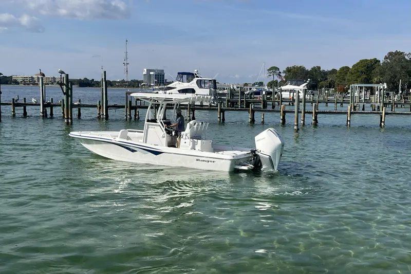 Slide: The Image of 2026 Ranger 2510 Bay boat cruising in a marina with clear water and docks. - 22
