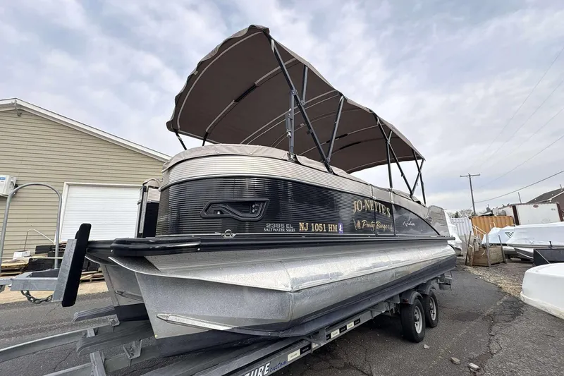 Slide: The Image of 2018 Avalon 2385 EL pontoon boat on trailer with canopy, parked outdoors. - 2