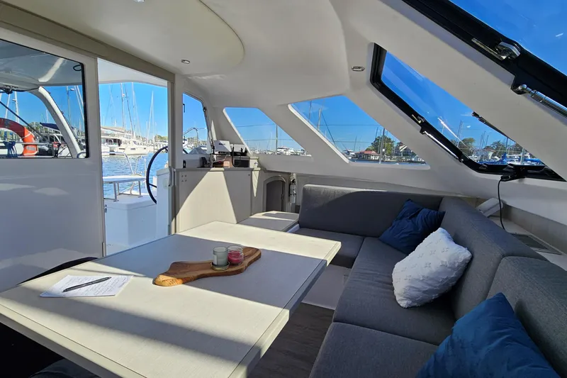 Slide: The Image of Interior of 2022 Seawind 1160 Lite catamaran with modern seating and marina view. - 6