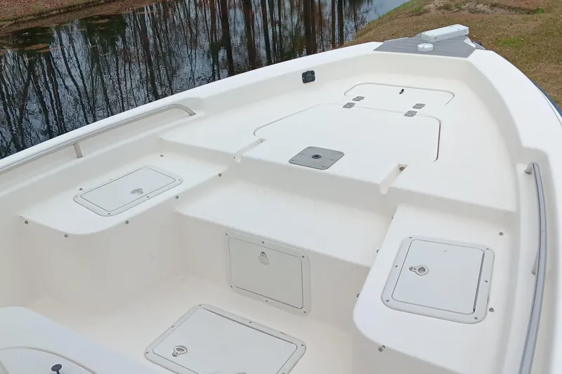 Slide: The Image of 2002 Sea Hunt Navigator 22 boat deck with storage compartments by a calm lake. - 8