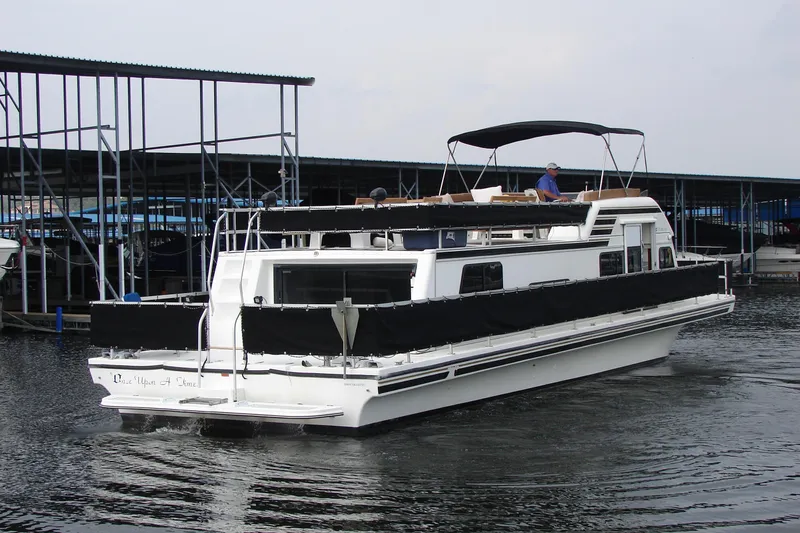 Slide: The Image of 1997 Gibson 47 Sport Houseboat docked at marina, featuring black canopy and sleek design. - 10