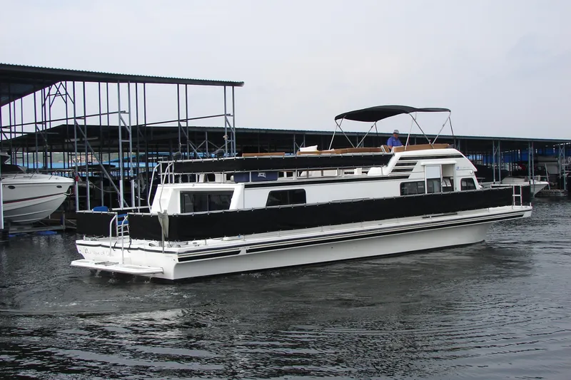 Slide: The Image of 1997 Gibson 47 Sport Houseboat docked at marina, featuring black canopy and sleek design. - 11