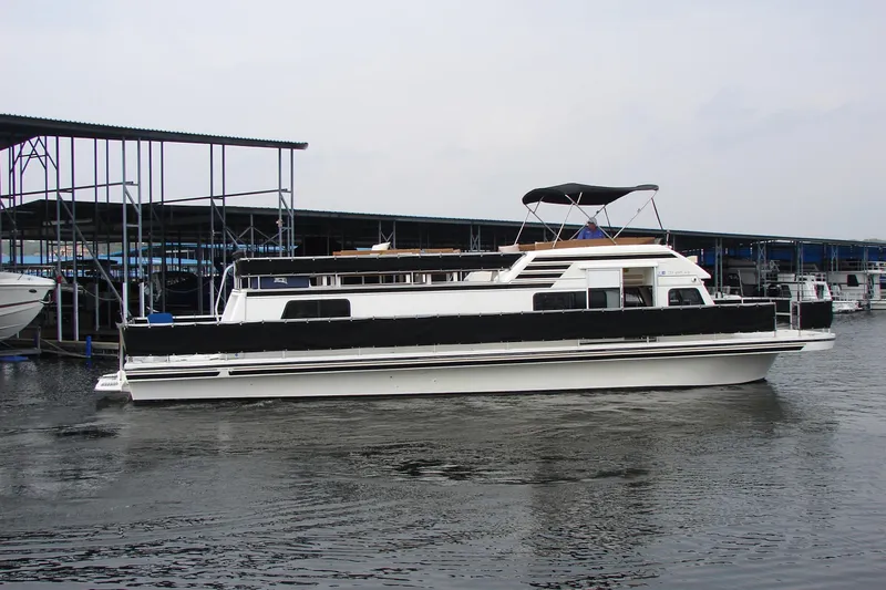 Slide: The Image of 1997 Gibson 47 Sport Houseboat docked at marina, featuring sleek design and spacious deck. - 12