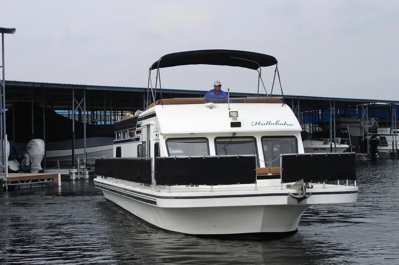 Slide: The Image of 1997 Gibson 47 Sport Houseboat on water, featuring a canopy and docked boats in the background. - 17