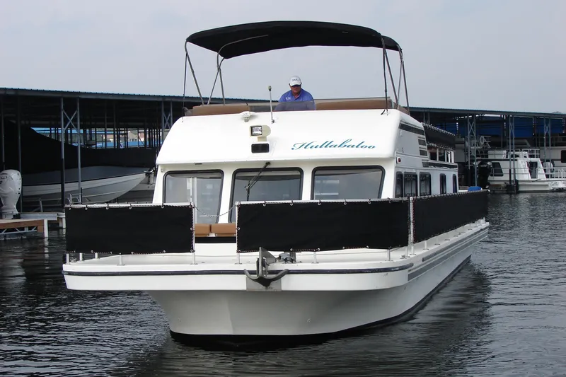Slide: The Image of 1997 Gibson 47 Sport Houseboat on water, featuring a covered upper deck. - 19