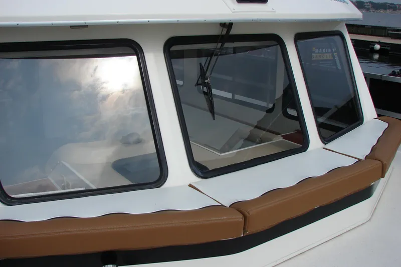 Slide: The Image of 1997 Gibson 47 Sport Houseboat with brown seating and large windows reflecting the sky. - 23
