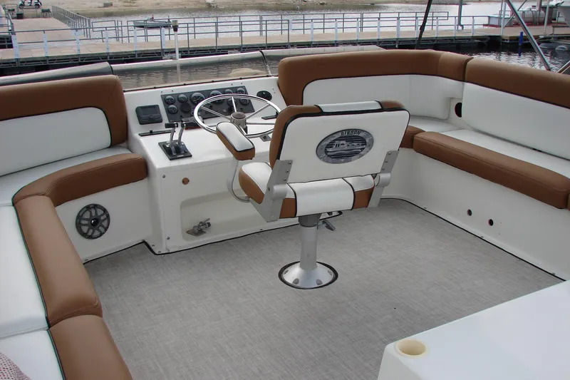 Slide: The Image of 1997 Gibson 47 Sport Houseboat helm with brown and white seating, docked at marina. - 34
