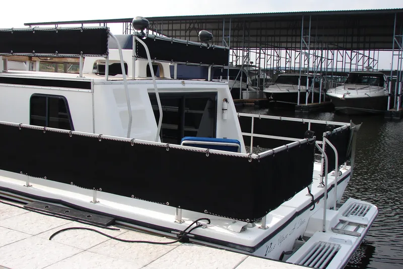 Slide: The Image of 1997 Gibson 47 Sport Houseboat docked at marina, featuring black rail covers. - 41