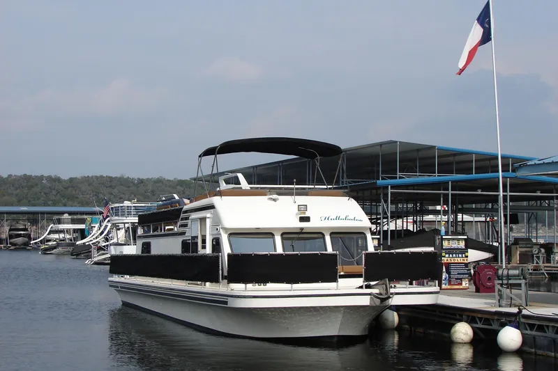 Slide: The Image of 1997 Gibson 47 Sport Houseboat docked at marina with flag in background. - 44