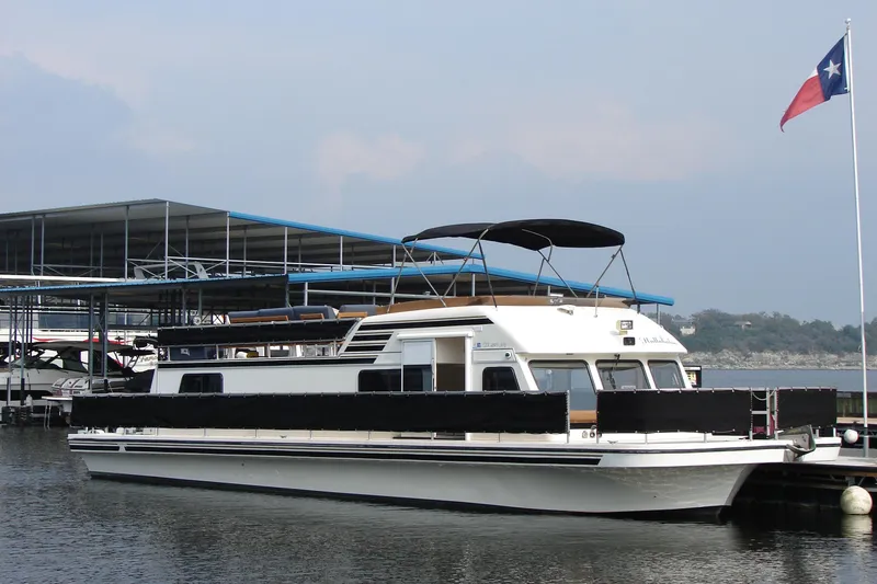 Slide: The Image of 1997 Gibson 47 Sport Houseboat docked near a marina with a Texas flag. - 46