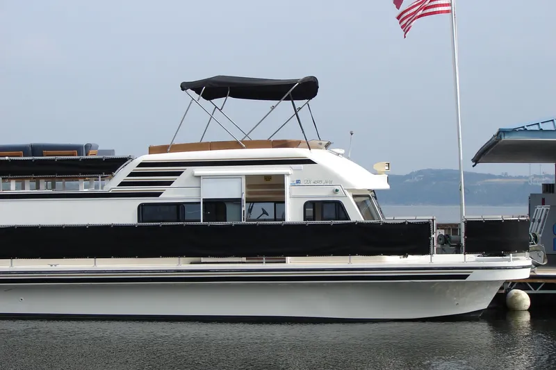 Slide: The Image of 1997 Gibson 47 Sport Houseboat docked with American flag in background. - 49