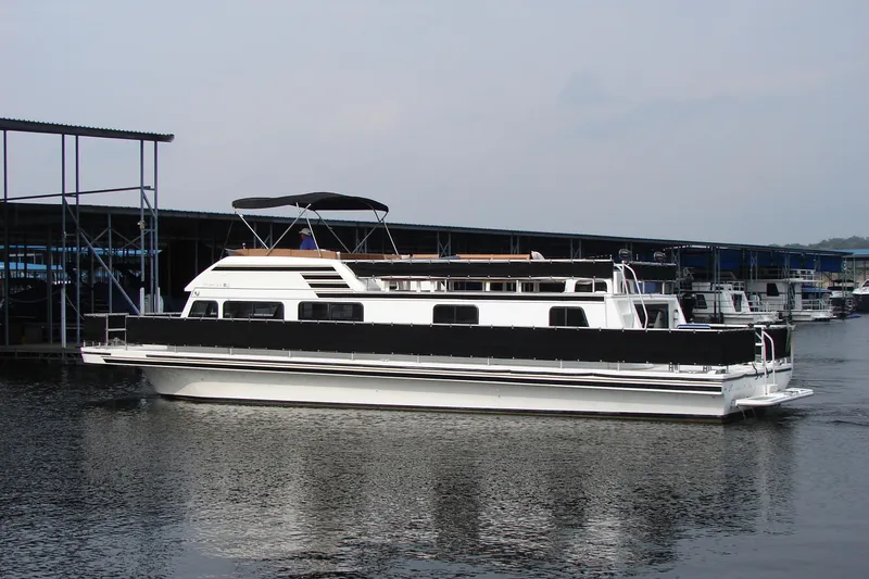 Slide: The Image of 1997 Gibson 47 Sport Houseboat docked on calm water, featuring a sleek design. - 5